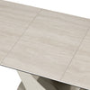 Close-up of a light beige stone-look rectangular table with a modern metallic support base, showing the tabletop seams and a portion of the base against a white background.
