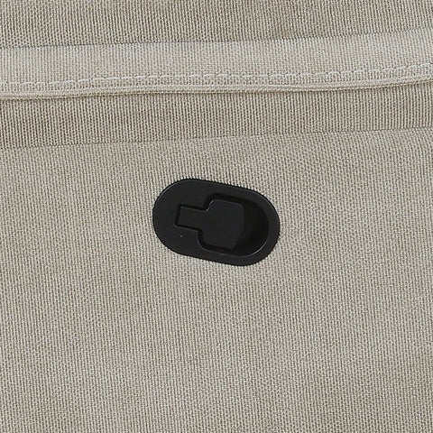 Close-up of a light beige textured fabric sofa with a black oval plastic hook-and-loop fastener.