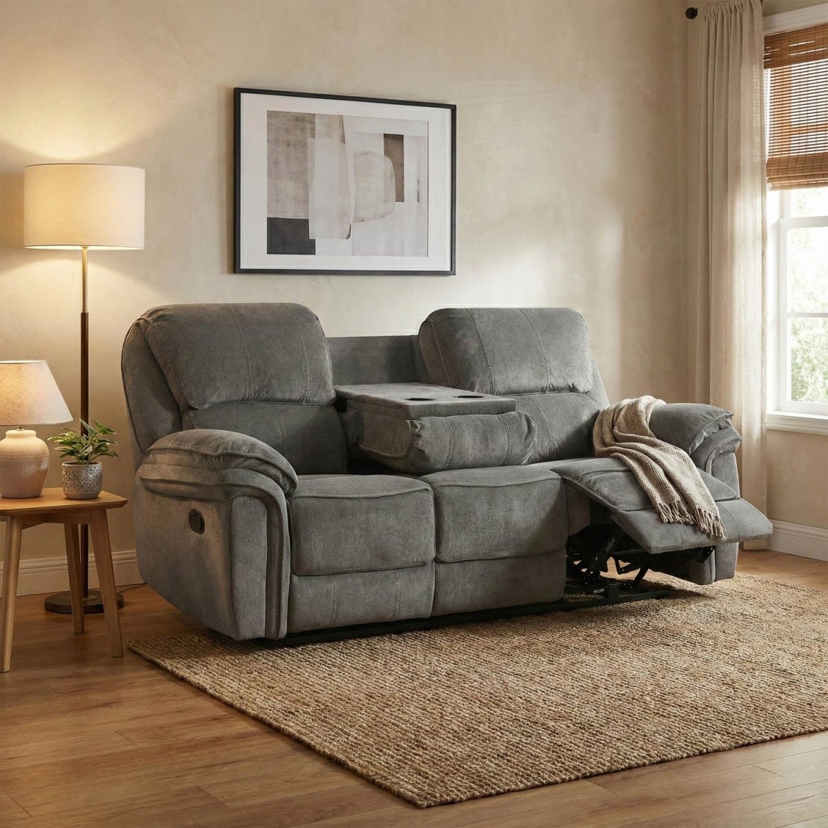 Gray recliner sofa in a living room setting with a lamp, side table, and framed picture on the wall.