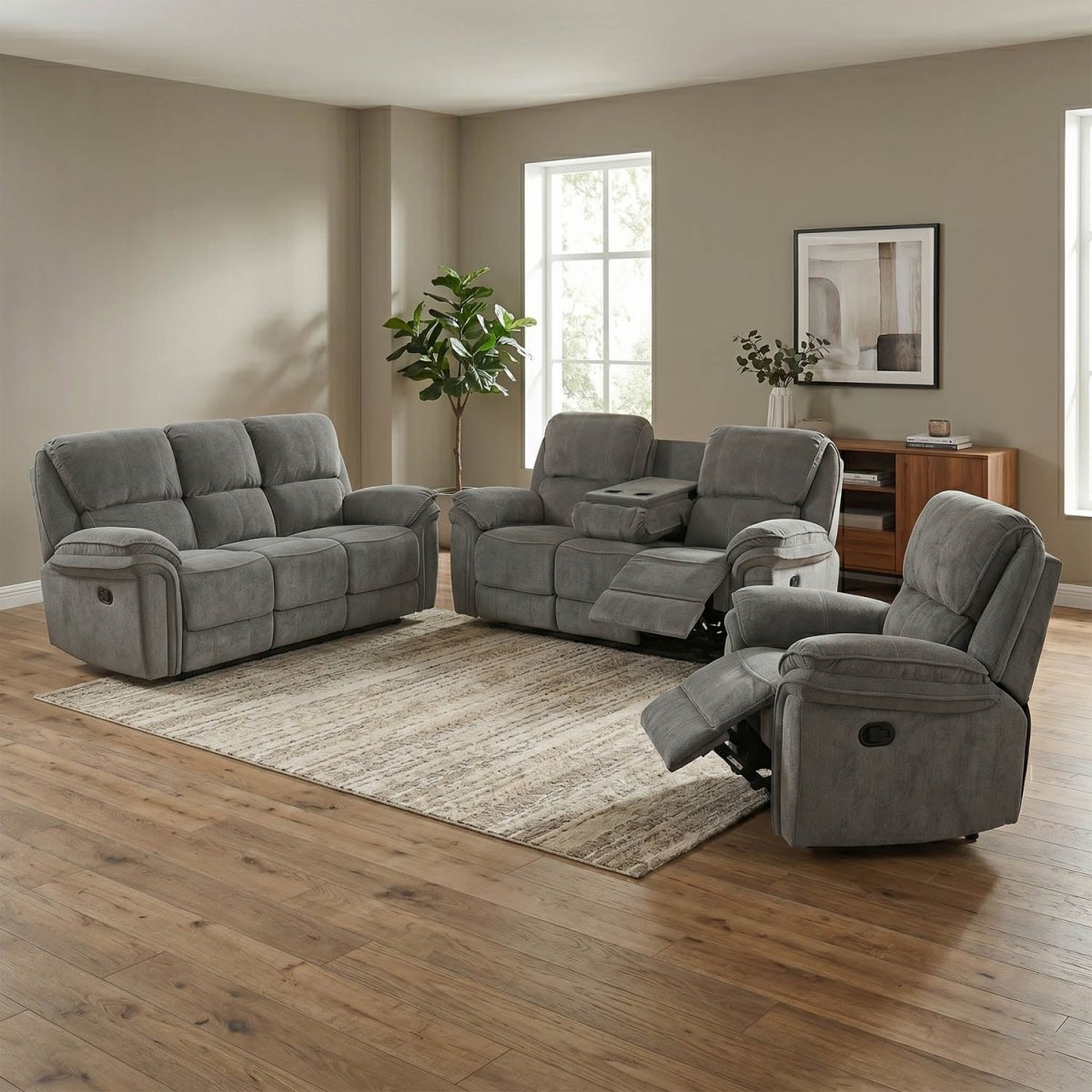 A three-piece gray reclining living room furniture set including a loveseat, a recliner, and a matching armchair, arranged on a neutral rug in a modern living room with wood floors.