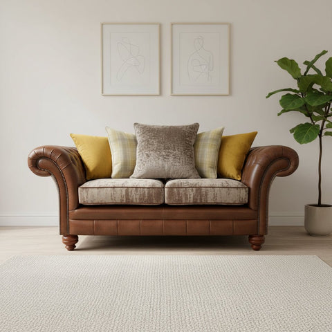 Brown leather sofa with patterned cushions against a rustic brick wall.